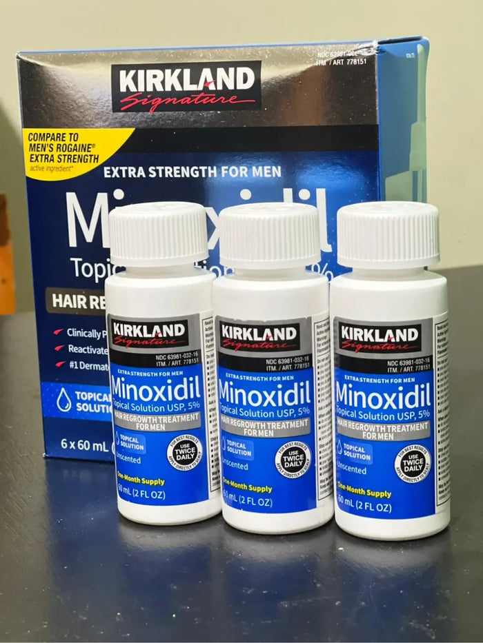 Imagem real de três frascos de Minoxidil Kirkland 5% com a caixa original ao fundo, representando o tratamento completo para crescimento de barba ou cabelo da MinoxFarma
